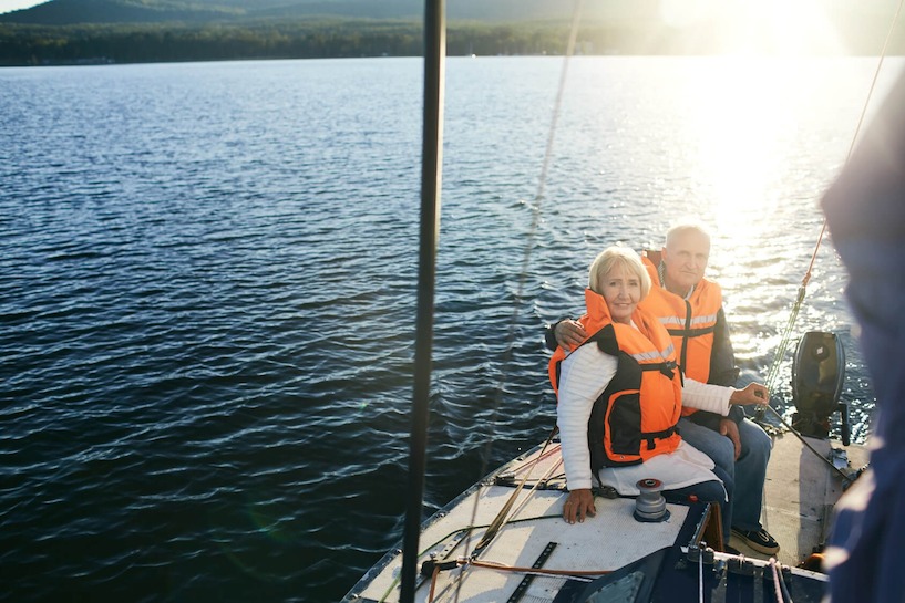 Auch bei einer Bootstour soll der Sonnenschutz nicht vergessen werden. segeln, Paar, Wasser, Segelboot, See, Rettungsweste, Schwimmweste, Senioren, Urlaub, Erholung, Sonnenuntergang